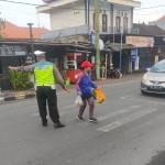 Aiptu Ketut Sutama Bantu Sebrangkan Nenek Yang Kesulitan Menyebrang .