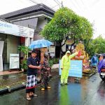 Hujan Mengiringi Prosesi Ngaben, Bhabinkamtibmas Polsek Dentim Bersama Babinsa, Linmas dan Pecalang Lakukan Pengamanan